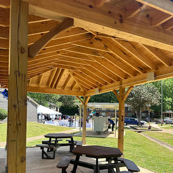 A wooden pavilion with picnic tables underneath