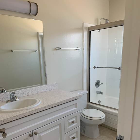 Bermuda Apts- white bathroom with vanity, toilet and shower door