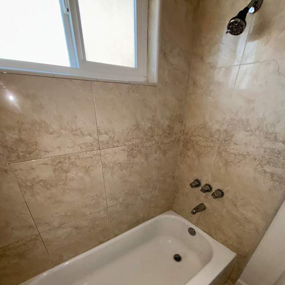 A bathroom with a tiled floor and a bathtub.