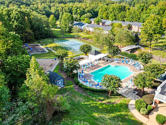 A pool surrounded by trees and a building in the background.