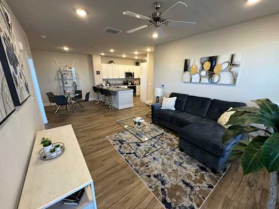A living room with a black couch and a ceiling fan.