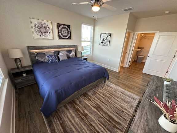 A bedroom with a blue bedspread and a ceiling fan.