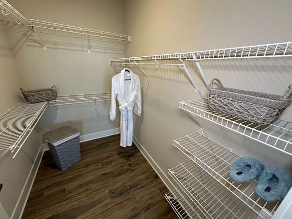 A white robe is hanging on a rack in a room with white shelves.