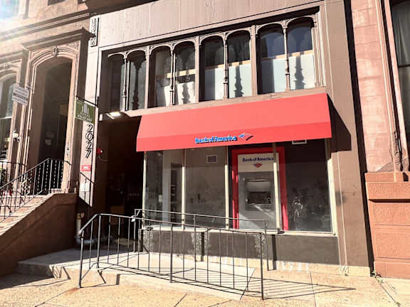 A Bank of America ATM is located on the corner of a street.