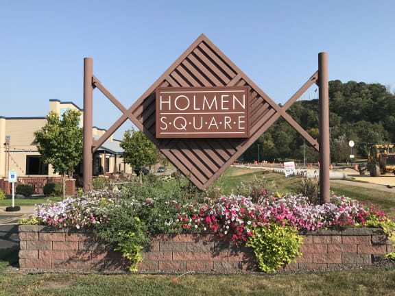 a sign for hollien square in front of a flower garden