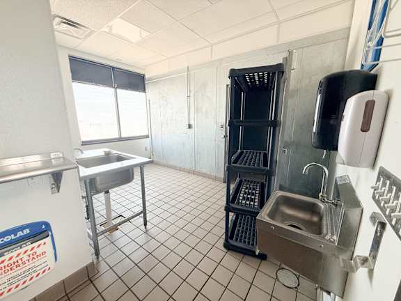 A clean, empty commercial kitchen with stainless steel appliances and white tiled floors.