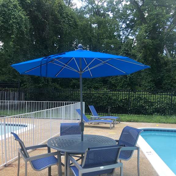 A blue umbrella is next to a pool.