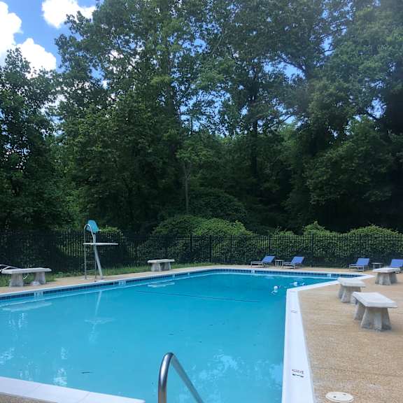A pool with a diving board and a metal ladder.