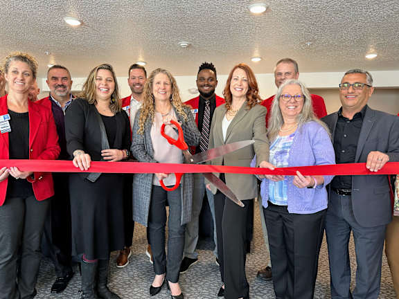 A group of people are gathered for a ribbon cutting ceremony.