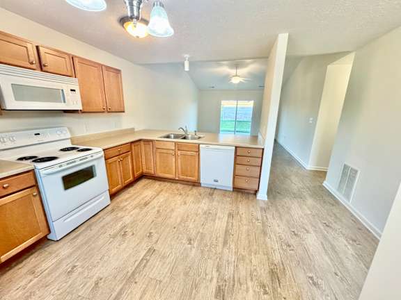 an empty kitchen with white appliances and wooden cabinets at Hawthorne Properties in Lafayette, IN 47905