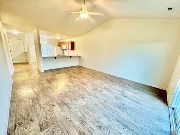 the living room and kitchen of an empty home with a ceiling fan at Hawthorne Properties in Lafayette, IN 47905
