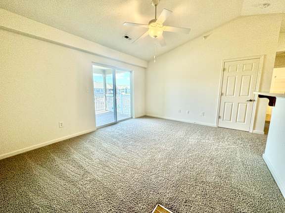 an empty living room with a ceiling fan and a door to a balcony  at Hawthorne Properties in Lafayette, IN 47905