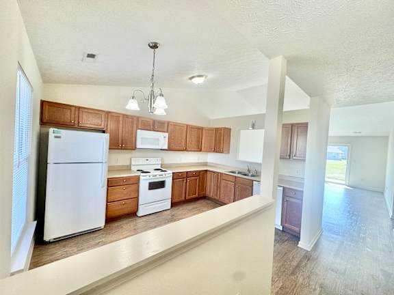 an empty kitchen with white appliances and wooden cabinets  at Hawthorne Properties in Lafayette, IN 47905