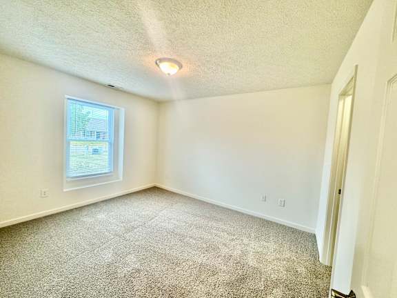 an empty room with carpet and a window at Hawthorne Properties in Lafayette, IN 47905
