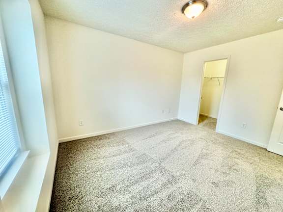 an empty living room with carpet and a door to a closet at Hawthorne Properties in Lafayette, IN 47905