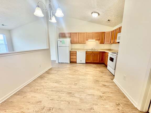 an empty kitchen with white appliances and wooden cabinets at Hawthorne Properties in Lafayette, IN 47905