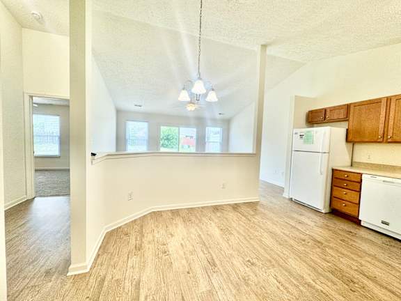 an empty kitchen and living room with white appliances and wood floors at Hawthorne Properties in Lafayette, IN 47905