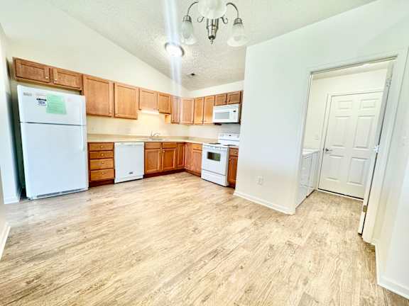 an empty kitchen with wood flooring and white appliances at Hawthorne Properties in Lafayette, IN 47905