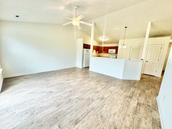 an empty living room with a ceiling fan and a kitchen at Hawthorne Properties in Lafayette, IN 47905