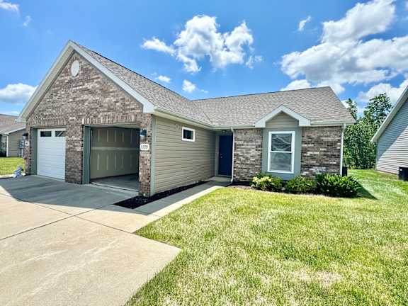 a tan and with a garage and a lawn at Hawthorne Properties in Lafayette, IN 47905
