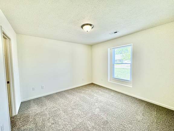 an empty room with carpet and a window at Hawthorne Properties in Lafayette, IN 47905