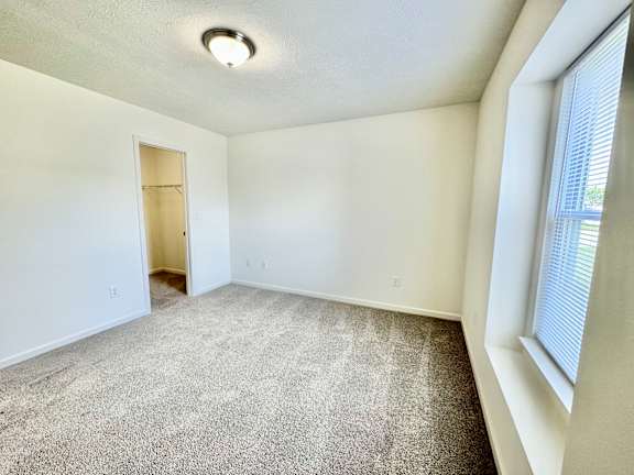an empty living room with carpet and a door to a closet at Hawthorne Properties in Lafayette, IN 47905