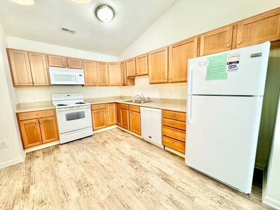 an empty kitchen with wooden cabinets and white appliances at Hawthorne Properties in Lafayette, IN 47905