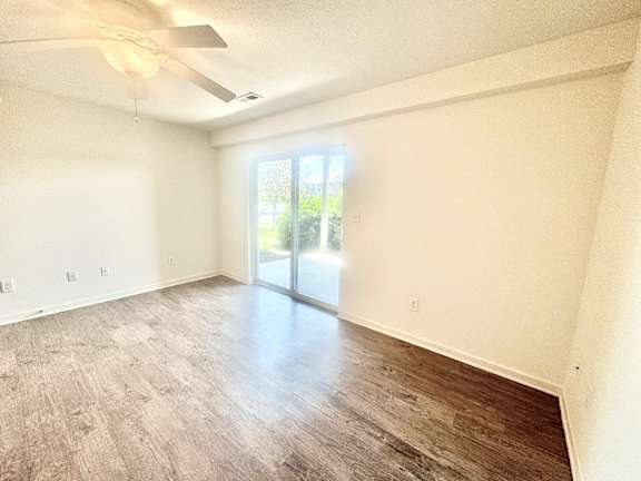 an empty living room with wood floors and a sliding glass door  at Hawthorne Properties in Lafayette, IN 47905