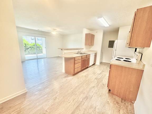 an empty kitchen and living room with wood flooring  at Hawthorne Properties in Lafayette, IN 47905