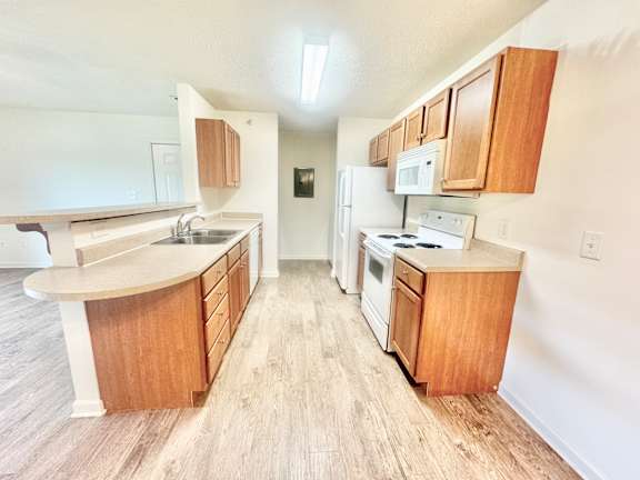 an empty kitchen with wooden cabinets and white appliances  at Hawthorne Properties in Lafayette, IN 47905