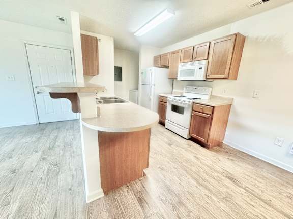 an open kitchen with white appliances and wooden cabinets  at Hawthorne Properties in Lafayette, IN 47905