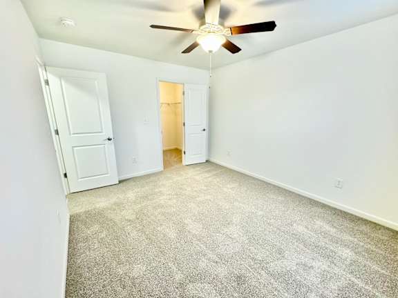 an empty living room with white walls and a ceiling fan  at Hawthorne Properties in Lafayette, IN 47905
