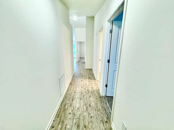 an empty hallway with white walls and a wood floor at Hawthorne Properties in Lafayette, IN 47905