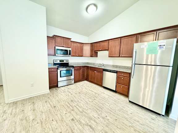 an empty kitchen with wooden cabinets and stainless steel appliances at Hawthorne Properties in Lafayette, IN 47905