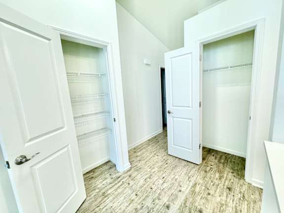 an empty closet with white doors and a wood floor at Hawthorne Properties in Lafayette, IN 47905