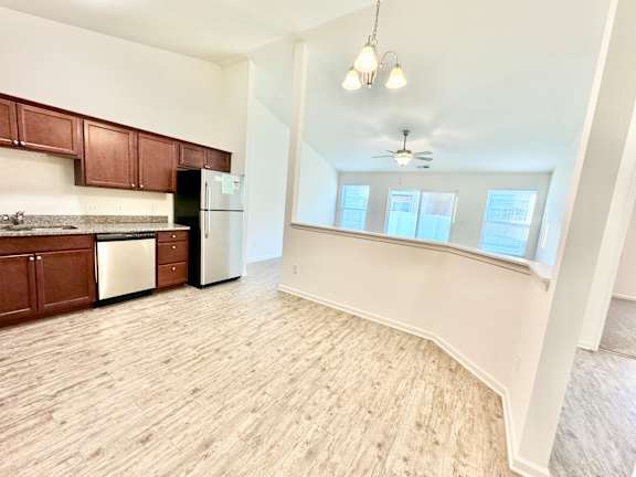 an empty kitchen and living room with wood flooring and white walls at Hawthorne Properties in Lafayette, IN 47905