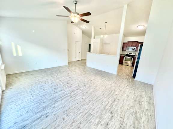 an empty living room with a ceiling fan and a kitchen at Hawthorne Properties in Lafayette, IN 47905