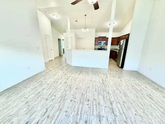 an empty living room and kitchen with white walls and wood flooring  at Hawthorne Properties in Lafayette, IN 47905