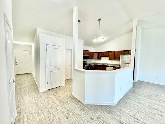 an empty living room and kitchen with white walls and wood flooring at Hawthorne Properties in Lafayette, IN 47905