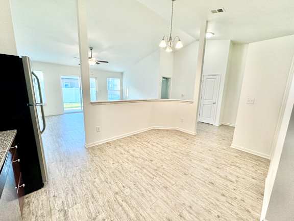 an empty living room with a kitchen and a refrigerator at Hawthorne Properties in Lafayette, IN 47905
