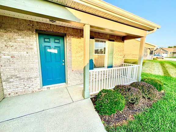 a blue door on the side of a building with a porch at Hawthorne Properties in Lafayette, IN 47905