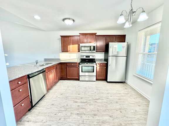an empty kitchen with wooden cabinets and stainless steel appliances at Hawthorne Properties in Lafayette, IN 47905