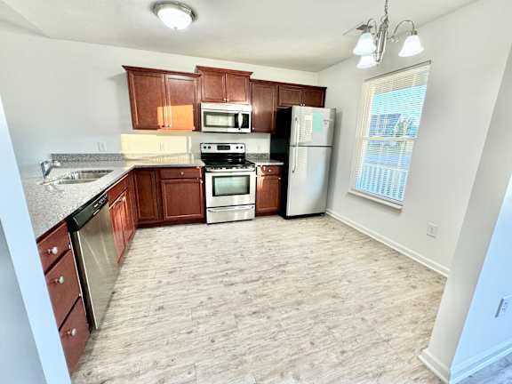an empty kitchen with wooden cabinets and stainless steel appliances at Hawthorne Properties in Lafayette, IN 47905