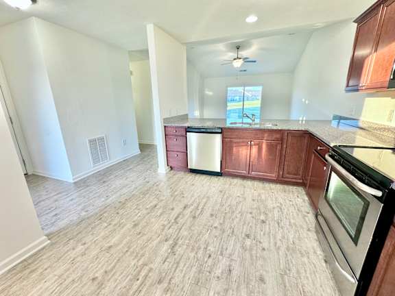 an empty kitchen and living room with wood flooring at Hawthorne Properties in Lafayette, IN 47905