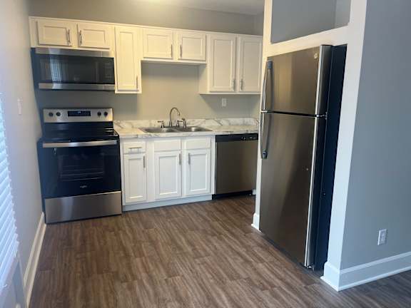 A kitchen with white cabinets and a black refrigerator.