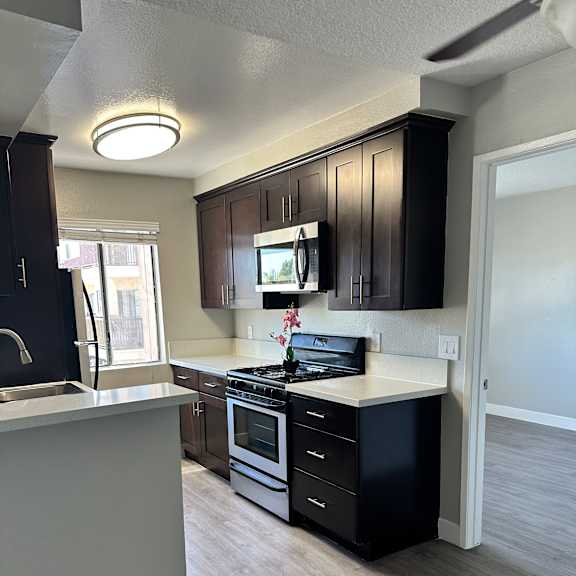 A modern kitchen with dark wood cabinets and a white ceiling.