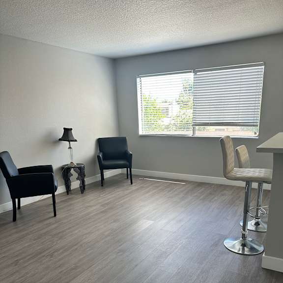 A room with a grey floor and a window with blinds.