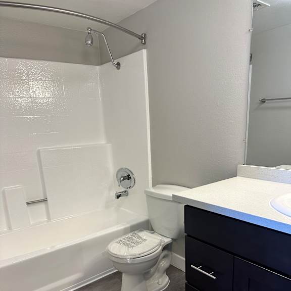A white toilet with a white lid and a white toilet paper holder.