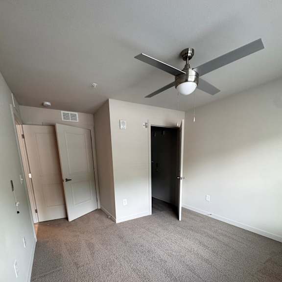 A white ceiling fan in a room with a built in cabinet.