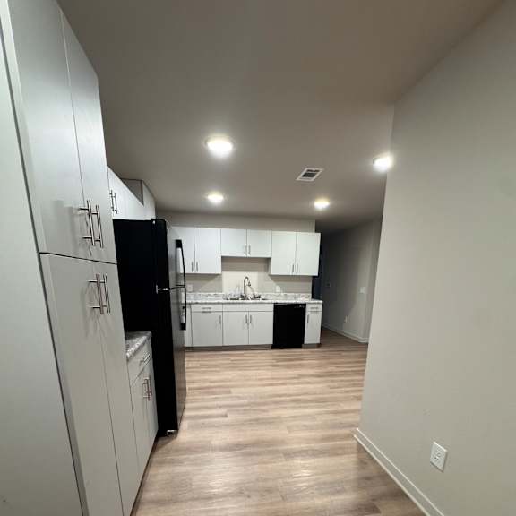 A modern kitchen with a white countertop and wooden walls.